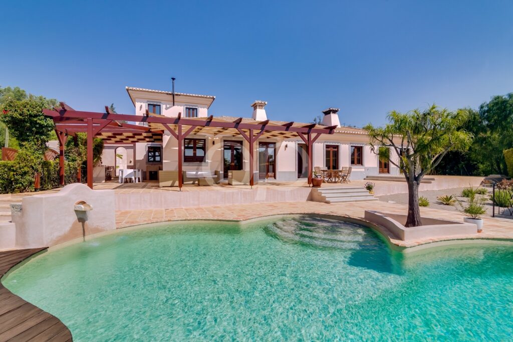 Außenansicht einer traditionellen Villa mit Swimmingpool und Pergola