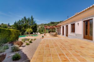 Großzügige, geflieste Terrasse mit Pergola und Zugang zum Garten