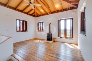 Wohnzimmer mit Holzofen und sichtbarer Holzbalkendecke