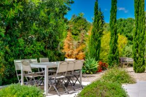 Área de refeições ao ar livre rodeada por jardins bem cuidados e maduros