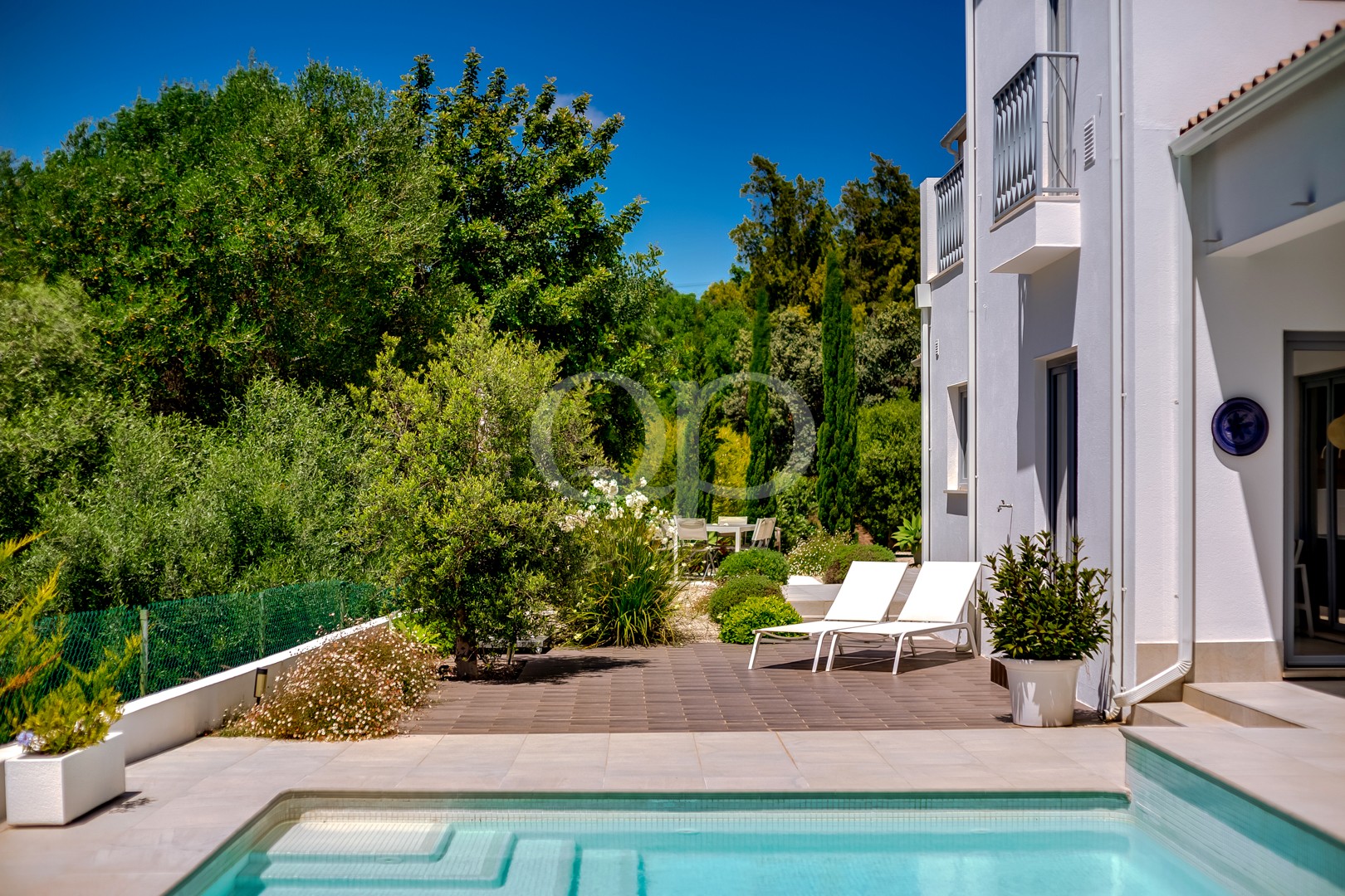 Poolterrasse mit Liegestühlen und gepflegtem Garten