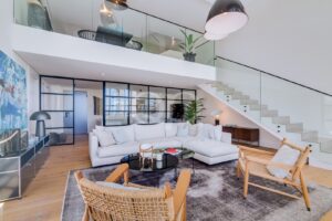 Double height sitting room with glass balustrade and open staircase