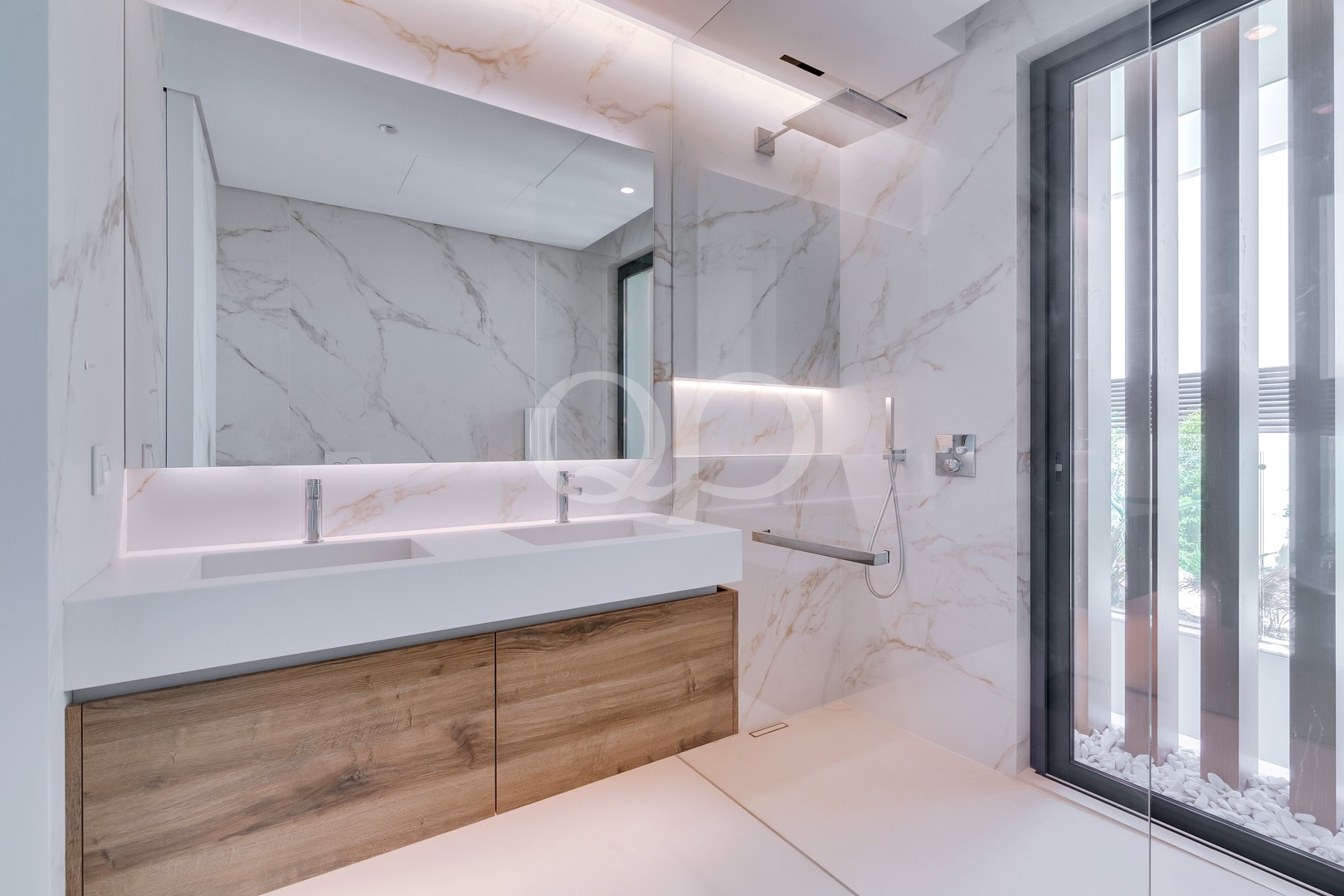 Salle de bains avec finitions en marbre, double vasque et douche à l'italienne