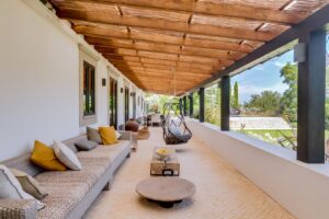Área de estar exterior coberta com vista para a piscina e os jardins