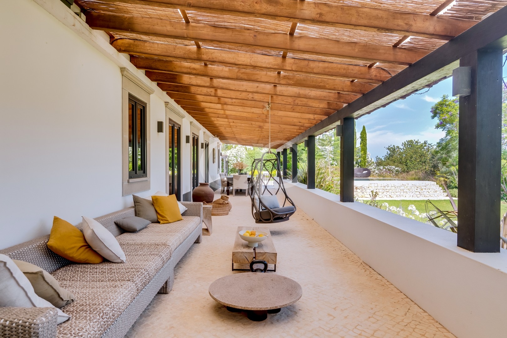 Área de estar exterior coberta com vista para a piscina e os jardins