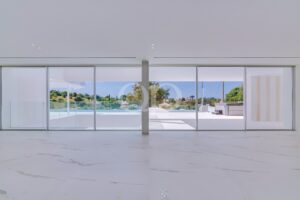 Heller, moderner, offener Wohnbereich mit atemberaubenden Marmorböden und großen Glastüren, die zum strahlenden Infinity-Pool führen