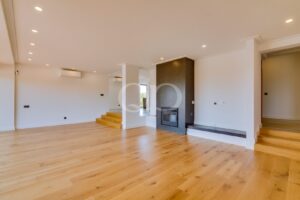 Open plan living area with fireplace, wooden flooring and modern staircase