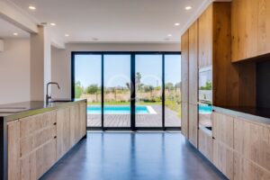 Contemporary kitchen with floor to ceiling windows and direct pool views