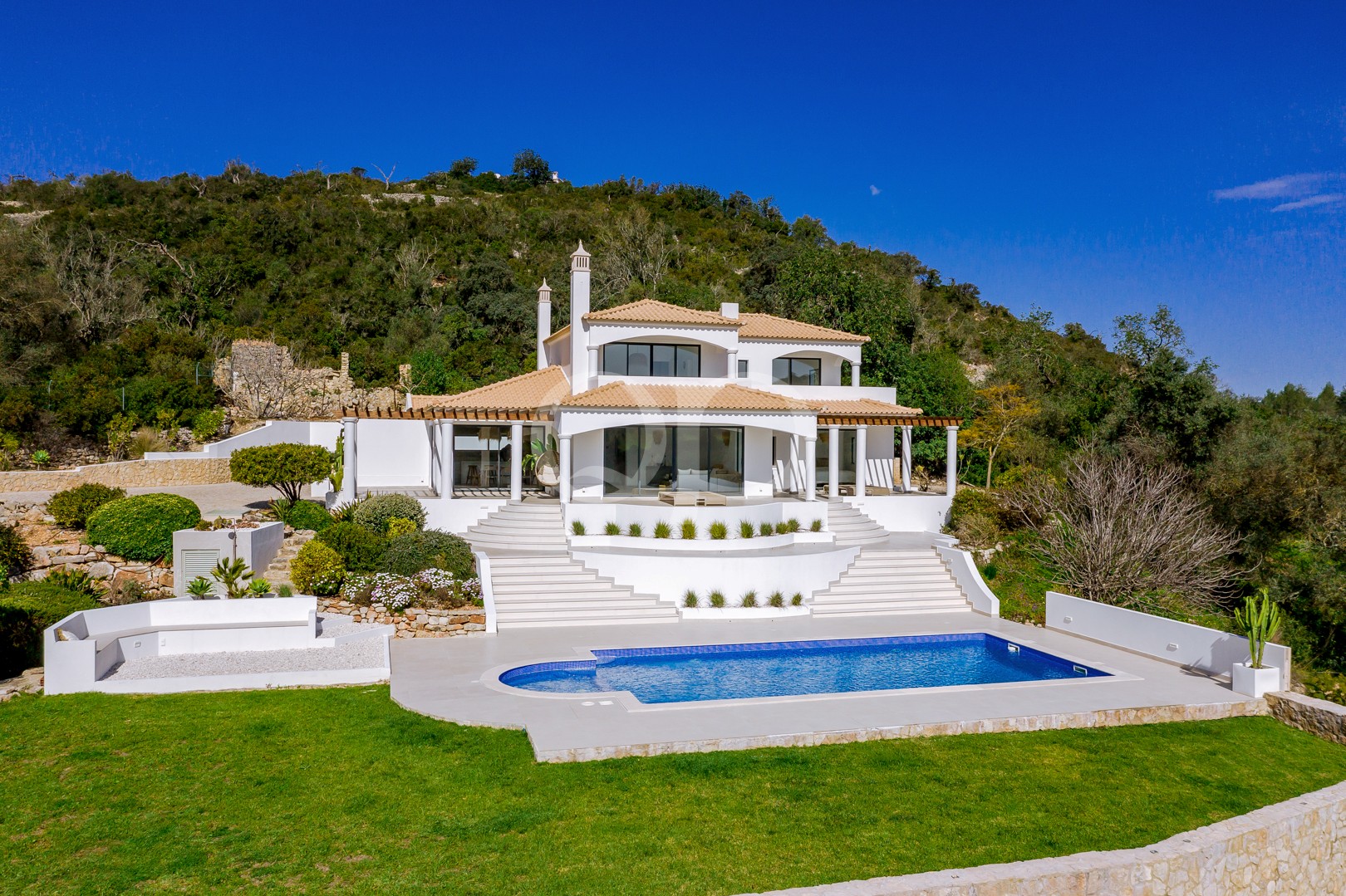 Moradia tradicional do Algarve com arquitetura caiada de branco, telhados de terracota, jardins bem cuidados e uma piscina privada