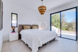 Quarto luminoso e contemporâneo, com texturas naturais, iluminação elegante e acesso a um terraço privado com vista para a vegetação