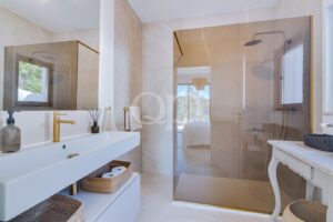 Casa de banho elegante com um espaçoso chuveiro tipo walk-in com efeito de chuva e acessórios requintados em ouro escovado