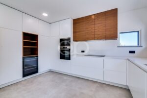 Cozinha moderna com eletrodomésticos integrados, armários em madeira e acabamentos minimalistas