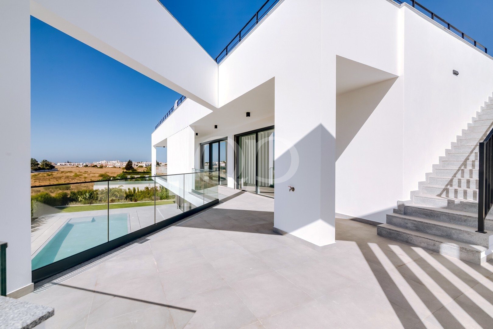 Terraço superior com balaustrada de vidro com vista para a piscina e para a paisagem circundante