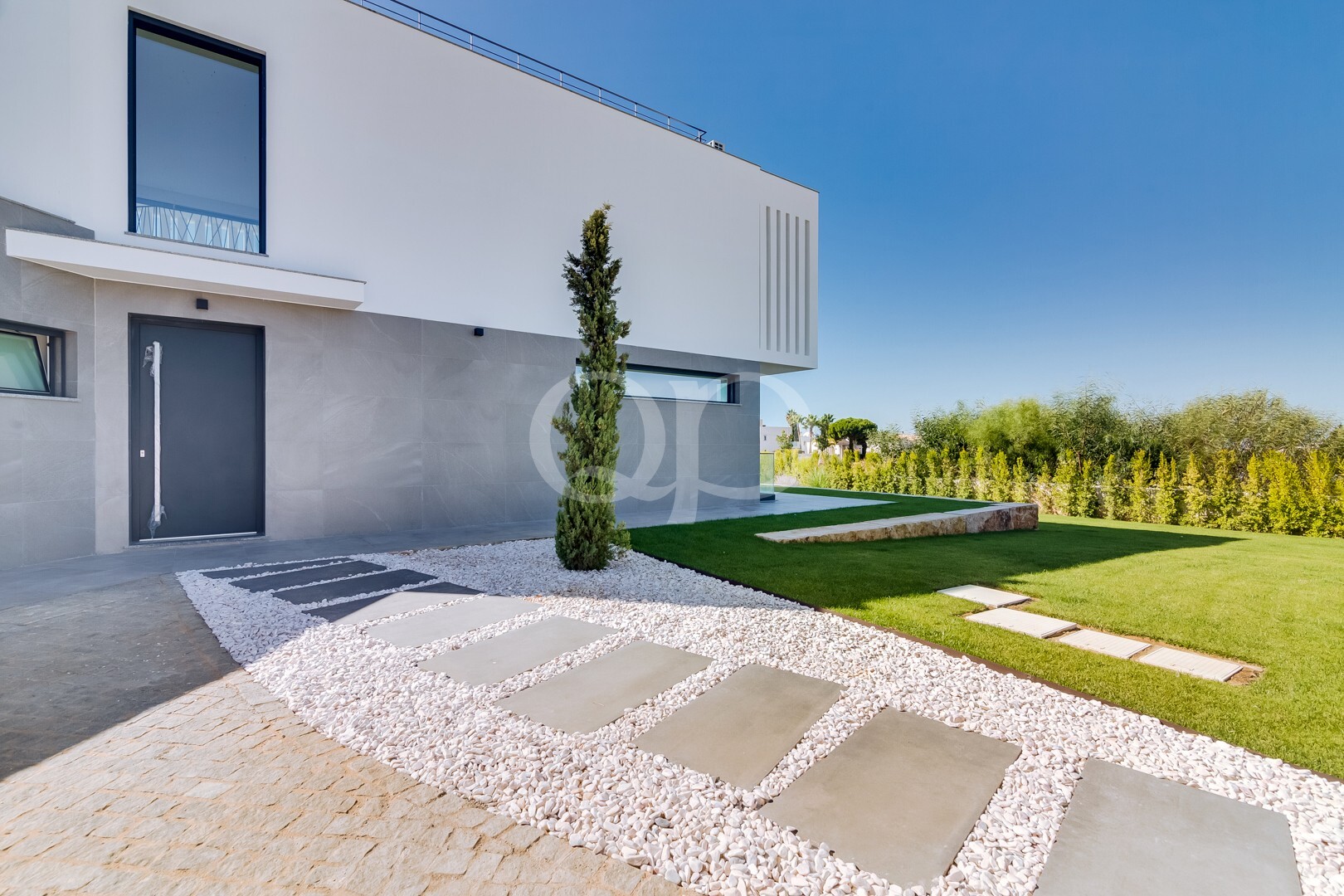 Exterior de uma moradia contemporânea com jardim ajardinado e elementos arquitetónicos de proteção visual