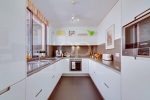 Cuisine avec appareils électroménagers encastrés, plans de travail en pierre et grande fenêtre