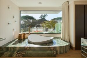 Chambre luxueuse avec baignoire îlot et vue sur le jardin