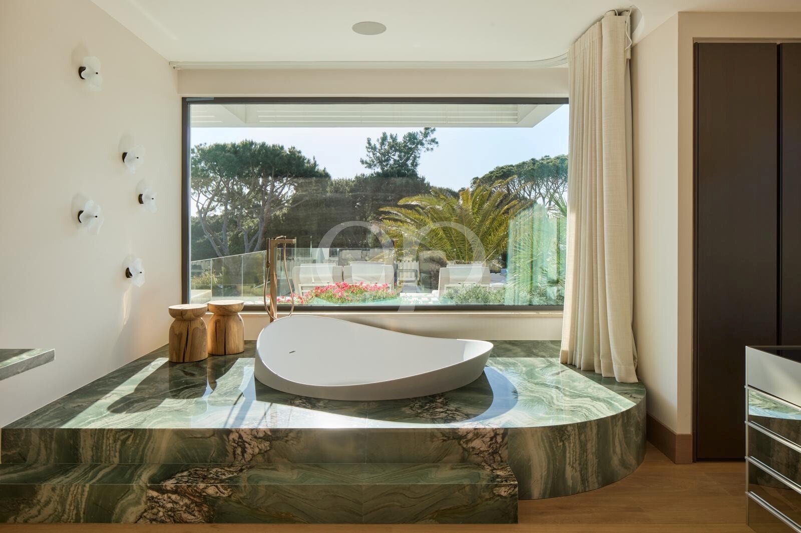 Chambre luxueuse avec baignoire îlot et vue sur le jardin