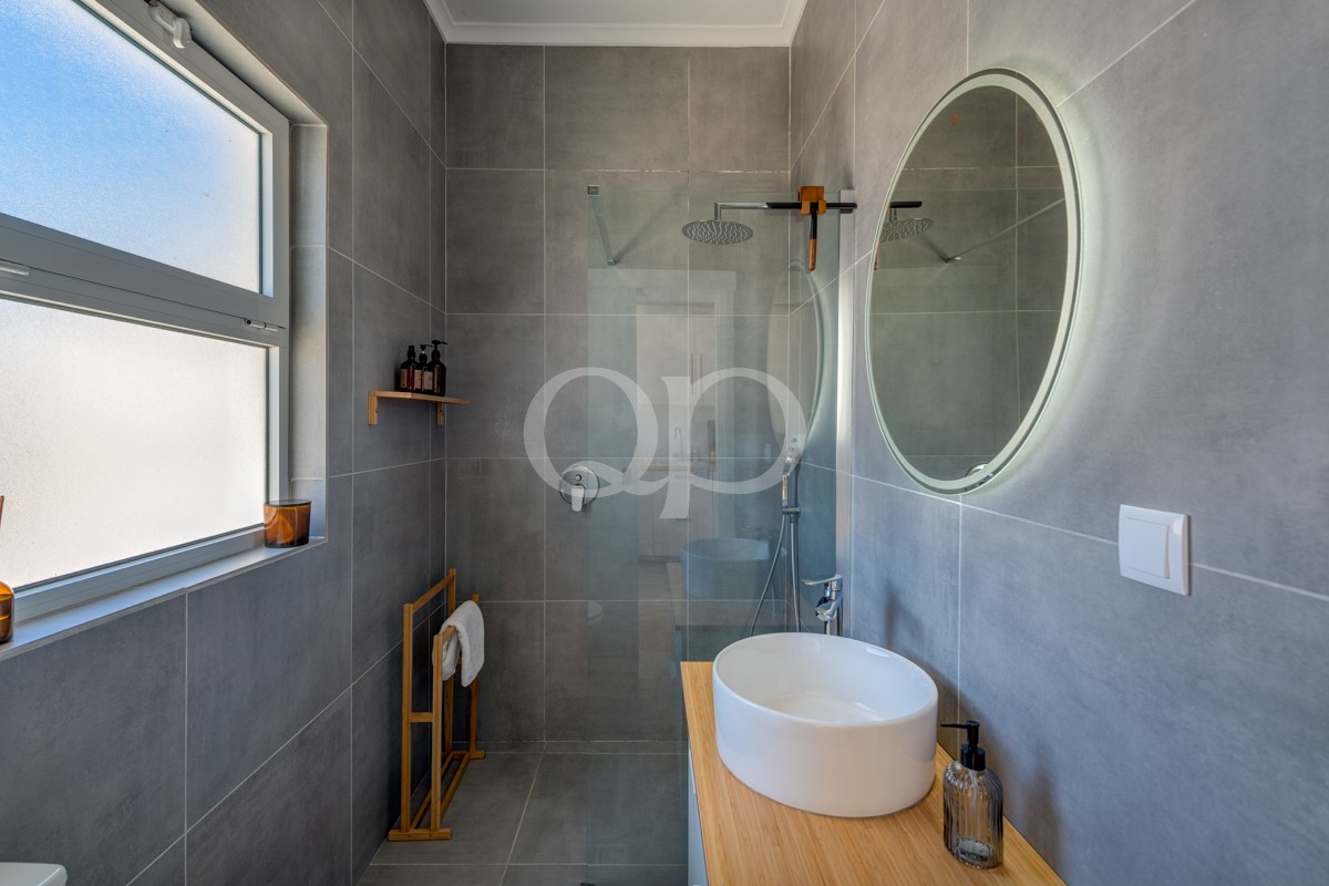 Casa de banho elegante e moderna, com cabina de duche em vidro e lavatório sofisticado