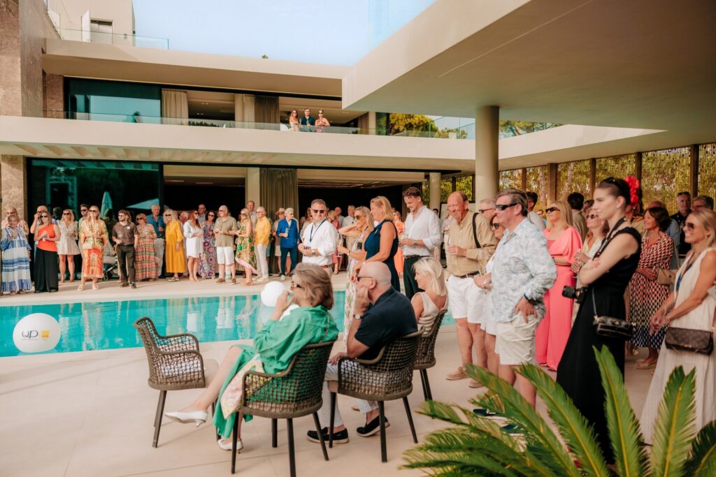 Guests gathered around the pool of a Quinta do Lago villa at the QP Savills Summer Party, with the house and evening light behind them