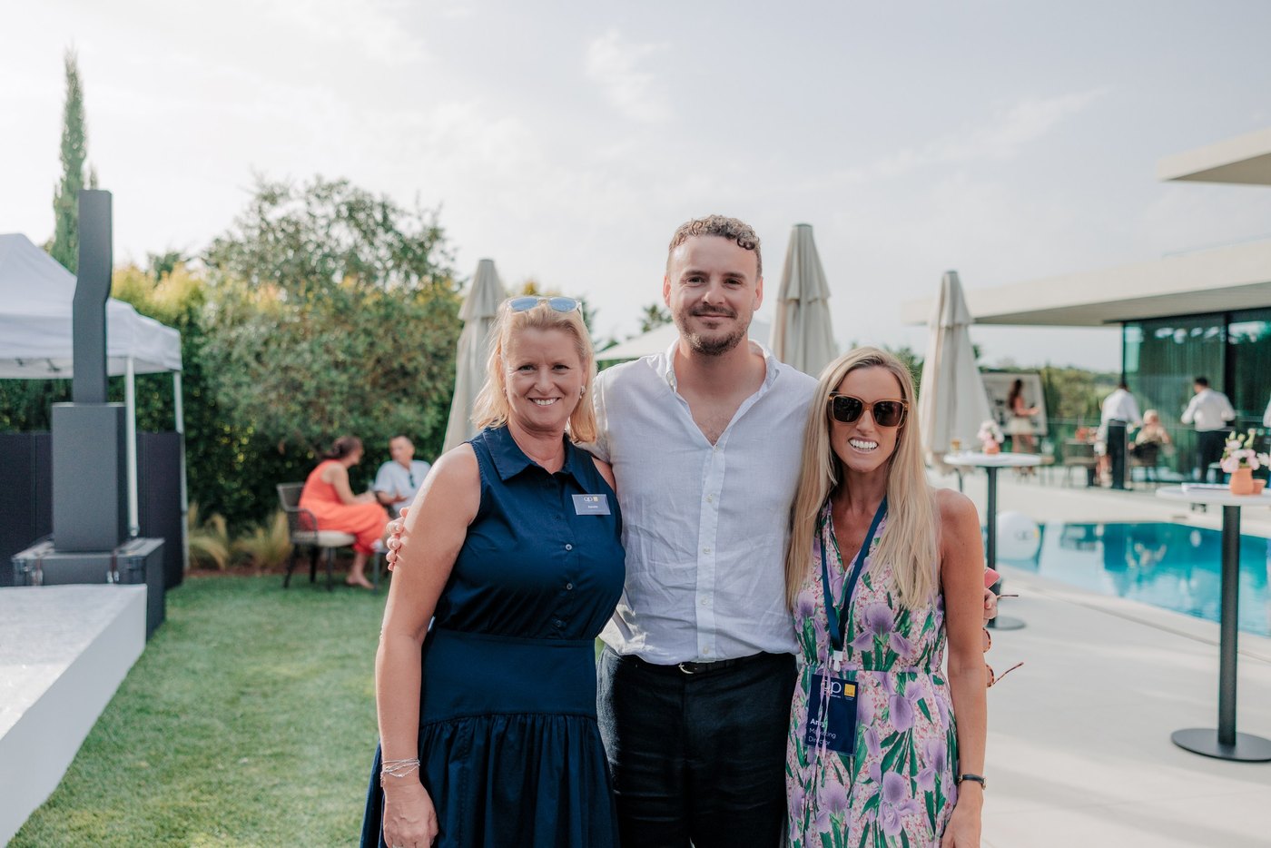 Drei Gäste, die gemeinsam am Pool fotografiert wurden, hinter ihnen Sonnenschirme und Liegestühle