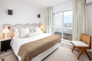 Bright bedroom with balcony access and coastal views