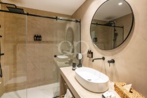 Bathroom with walk-in shower, round mirror and modern black fittings