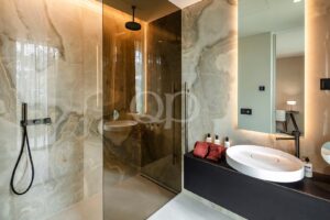 Casa de banho com acabamentos em mármore e cabina de duche em vidro