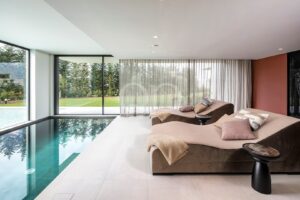 Piscina coberta com grandes espreguiçadeiras almofadadas