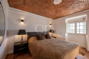 Spacious double bedroom with exposed brick ceiling and neutral interiors